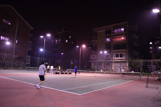 夜晚下灯光网球场几个人在打网球