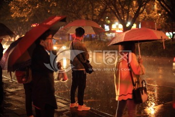 夜晚在路边打雨伞等公交的人们