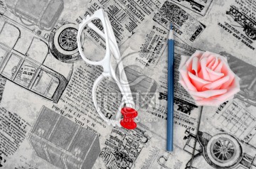 旧报纸上的眼镜铅笔玫瑰花
