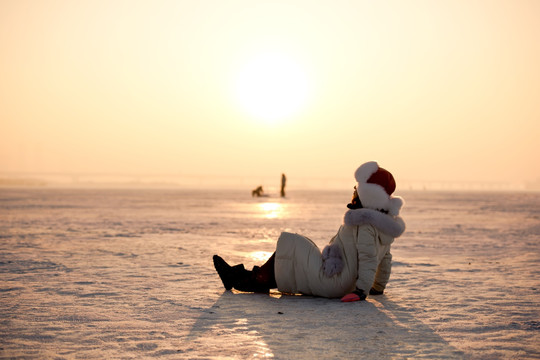 夕阳下坐在雪地里的女孩