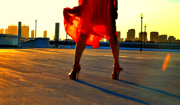 女人穿着红裙子站在夕阳下
