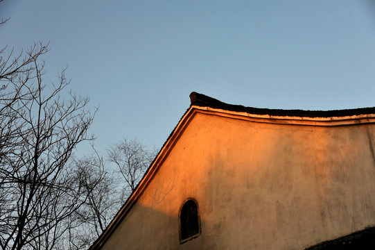 冬天夕阳照在树木与古建筑白墙上