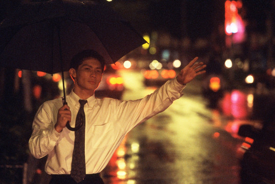 男主管夜间在雨中撑着伞