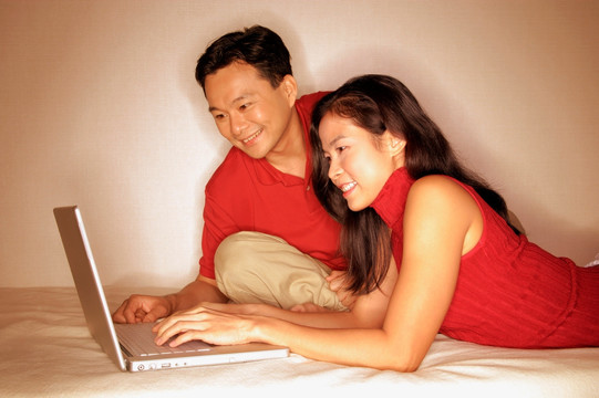 在床上使用笔记本电脑的夫妇