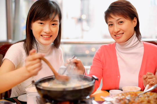 年轻妇女在餐馆喝汤