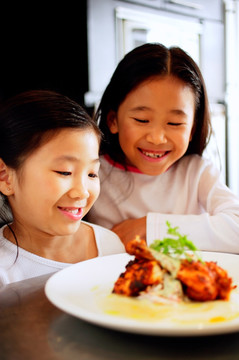 两个女孩看着盘子里的食物