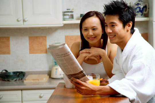在厨房里看报纸吃早餐的夫妇