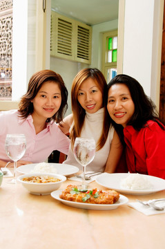 三个女人坐在餐桌旁微笑
