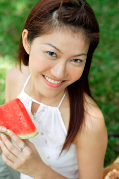 微笑的女人拿着一片西瓜
