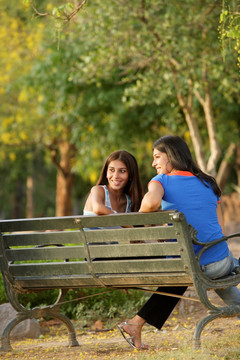 两个年轻女孩坐在公园长椅上