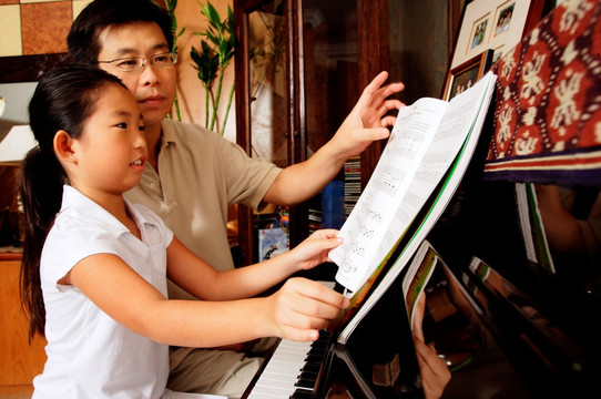 父亲和女儿坐在钢琴上