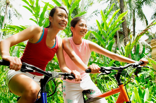 两个女孩微笑着骑着自行车