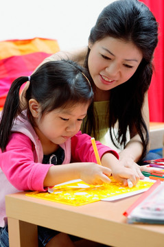 母亲和年幼的女儿在家画画
