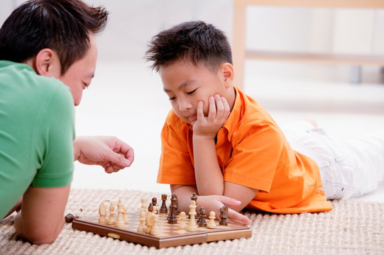 父子躺在地上下棋