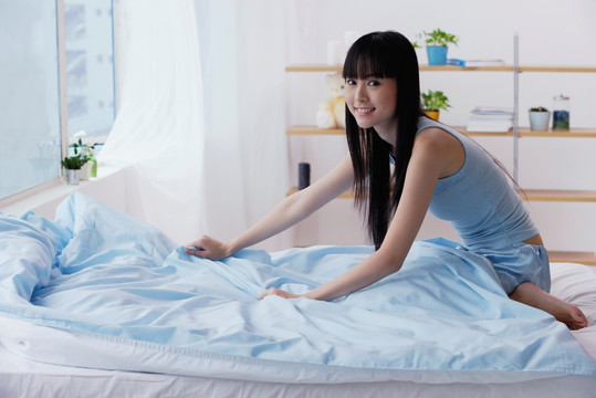 年轻女人整理她的床