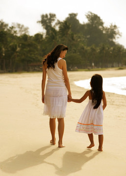 母亲和女儿手牵手在沙滩上散步
