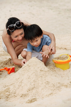 母亲和儿子在沙滩上建造沙堡