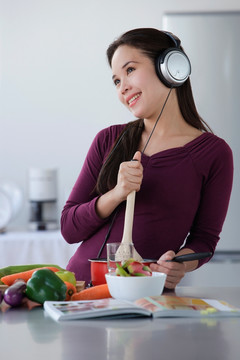 年轻女子一边做饭一边听音乐