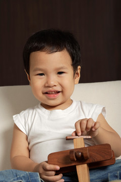 小男孩抱着木制玩具飞机