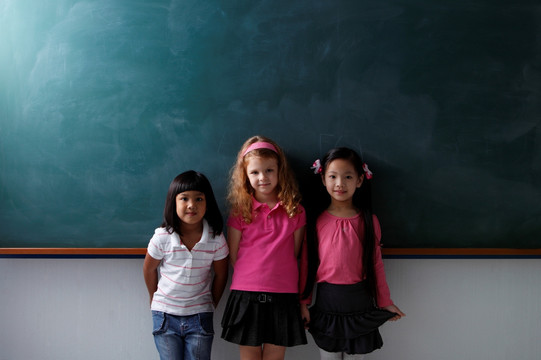 三个年轻女孩站在粉笔板前