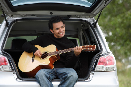 年轻人坐汽车玩吉他
