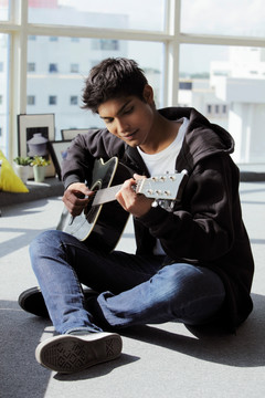 年轻人坐在地板上弹吉他