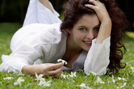 趴在草坪上拿着一朵花的女人