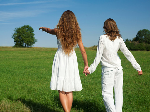 牵着手走在草坪上的两个女人