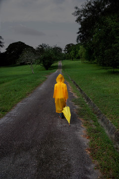 带着雨伞走在路上的男孩