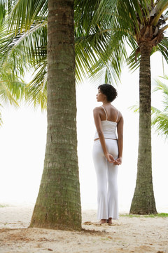 站在椰子树下看着大海的女人
