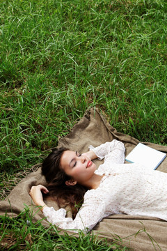 年轻女子躺在草地上闭着眼睛