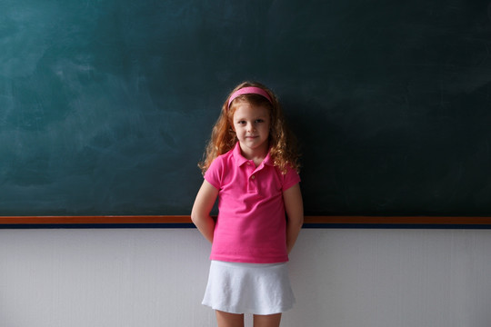 年轻的女孩站在黑板前面