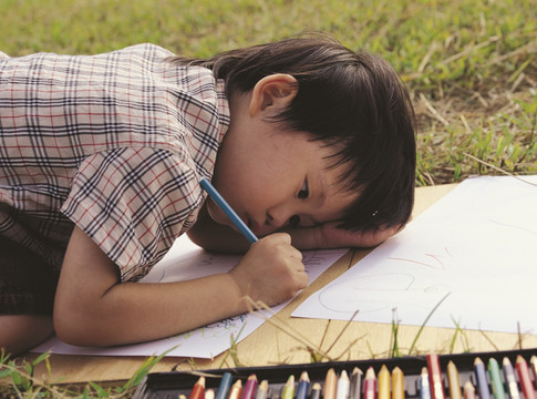一个小男孩在草地上画画