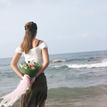 海边拿着一束束花的女人