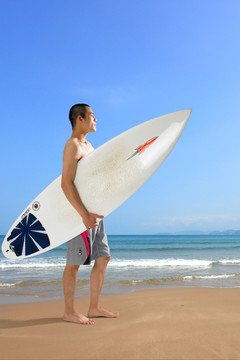 拿着冲浪板在沙滩上的男人
