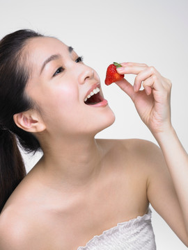 微笑的女人在吃草莓