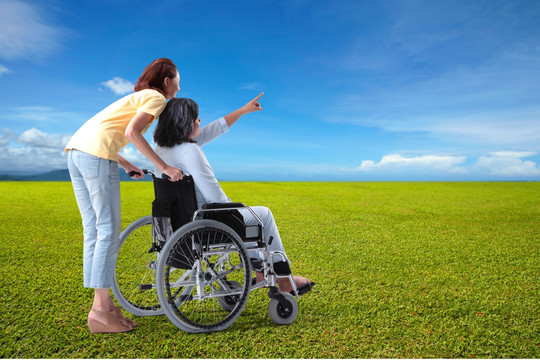 女人推着坐轮椅的母亲看风景