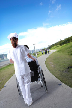 护士推着坐轮椅的病人散步