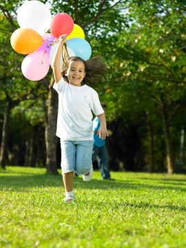 拿着气球泡的小女孩在公园奔跑