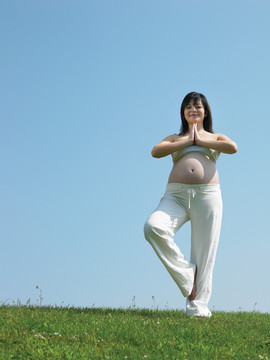 站在草坪上做瑜伽的女人