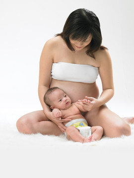 坐在毯子上看着小婴儿的孕妇妈妈