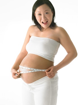 用皮尺测量肚子的孕妇