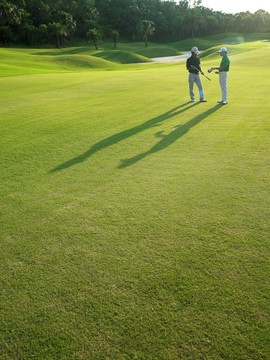 站在高尔夫球场草坪上的两个男人
