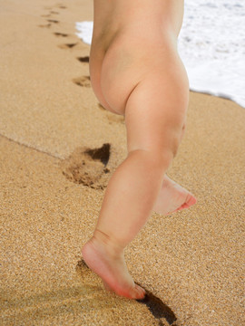 踩在沙滩上的小婴儿