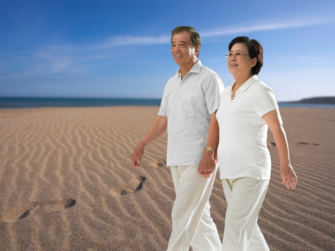 牵着手的老夫妇走在沙滩上