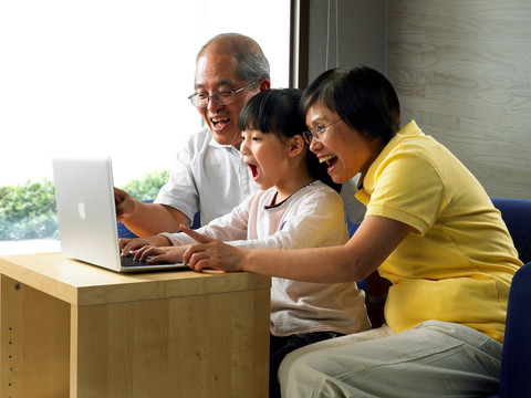 惊讶的祖父母和孙女看着的电脑