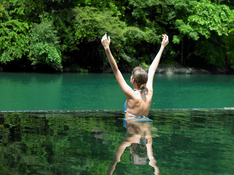 在溪水里举起双臂的年轻女人