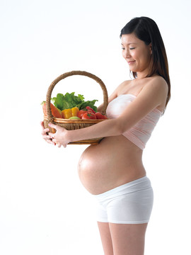 抱着一篮蔬菜的孕妇