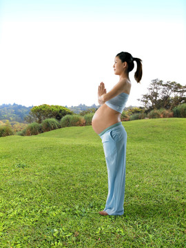 站在草坪上做瑜伽的孕妇