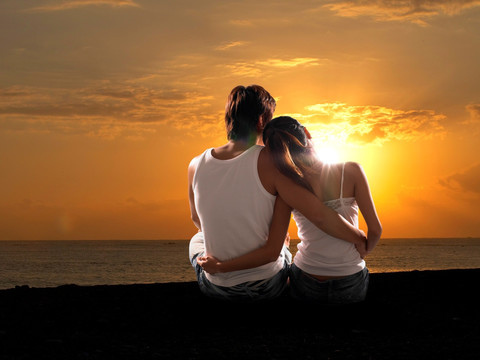 在海边看着夕阳的夫妇